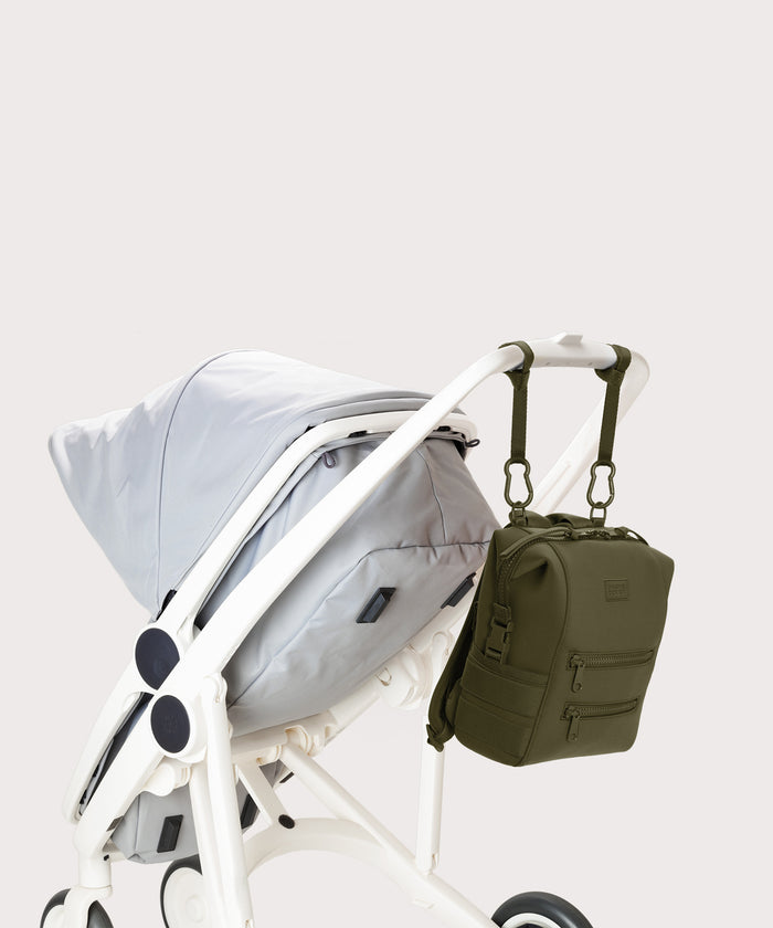 Dagne Dover small Indi Diaper Backpack in dark moss attached to a stroller.
