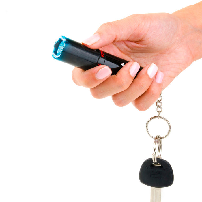 Lipstick-style stun gun held in hand, compact self-defense device with keyring.