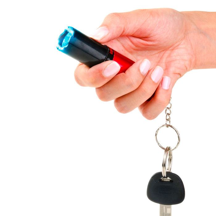 Lipstick-style stun gun held in hand, compact self-defense device with keyring red