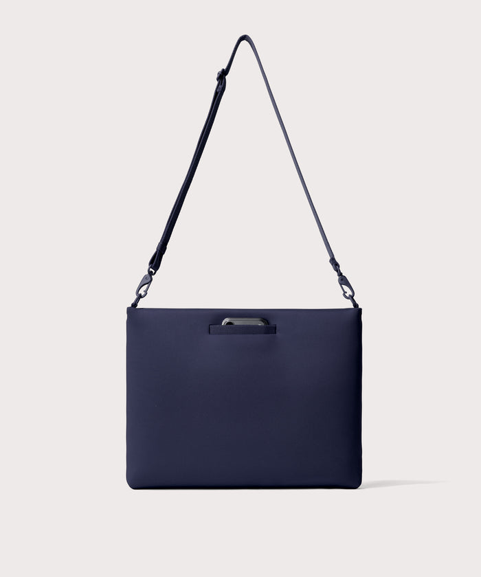 16 inch laptop shoulder bag in navy blue  seen from the back view showing phone pocket.