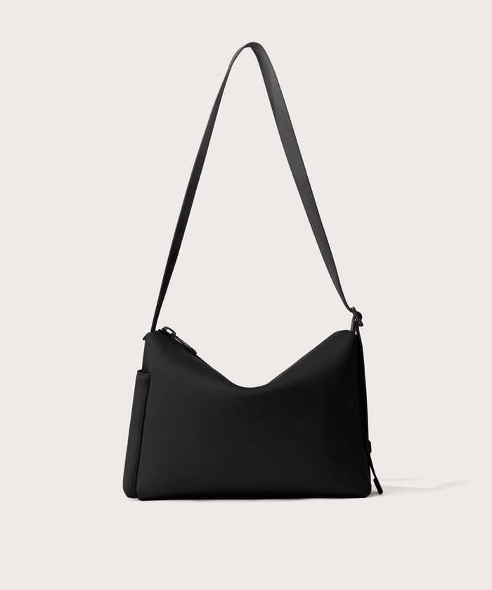 Shoulder bag in a  black seen from the back view showing phone pocket.