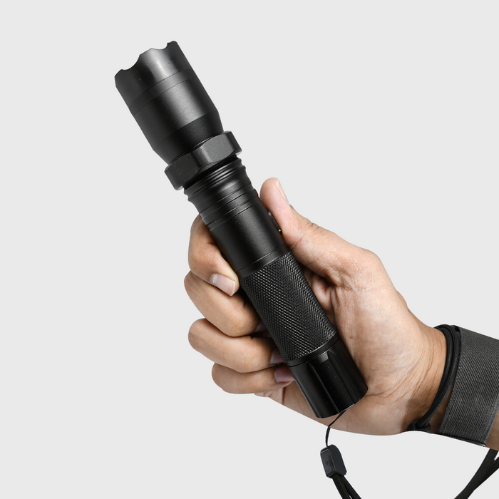 Hand holding a black tactical flashlight stun gun