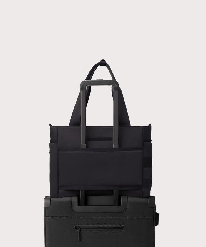 Dagne Dover large Wade Diaper Tote in black with the neoprene luggage sleeve attached to a suitcase handle.